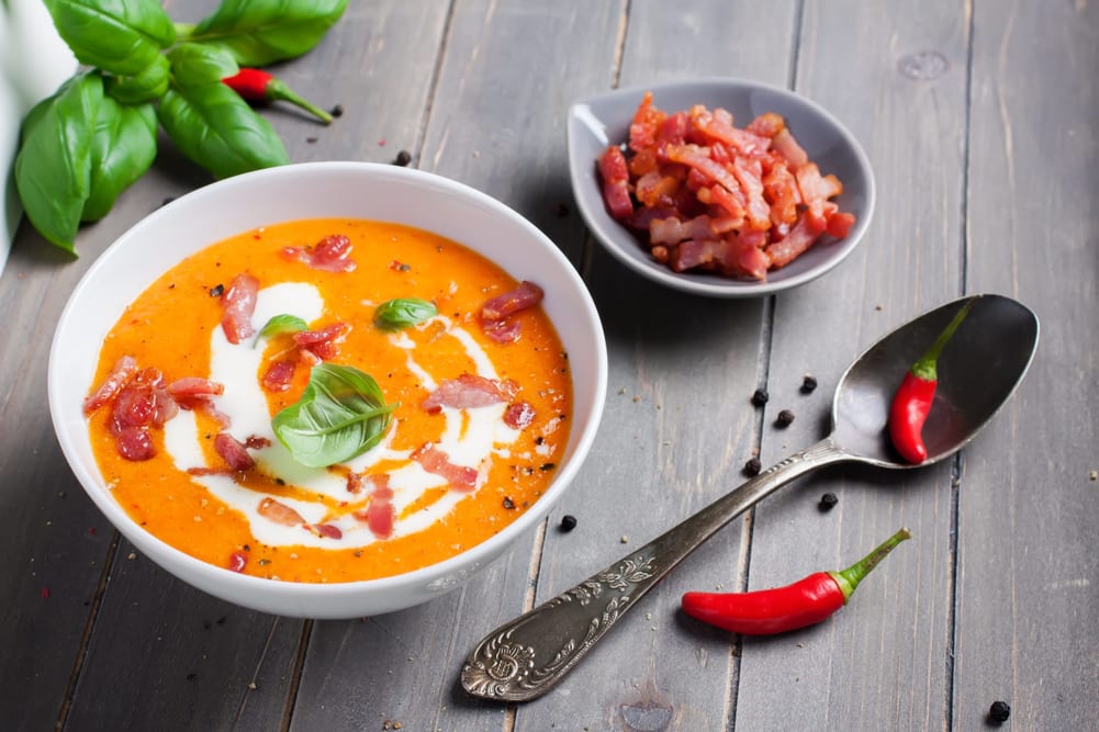 Bowl of sweet pepper cream carrot soup with bacon